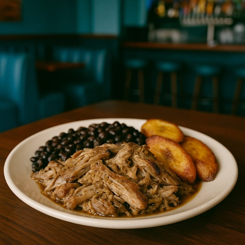 Papi's Restaurant's Cuban dish with shredded pork, black beans, and fried plantains on a white plate.